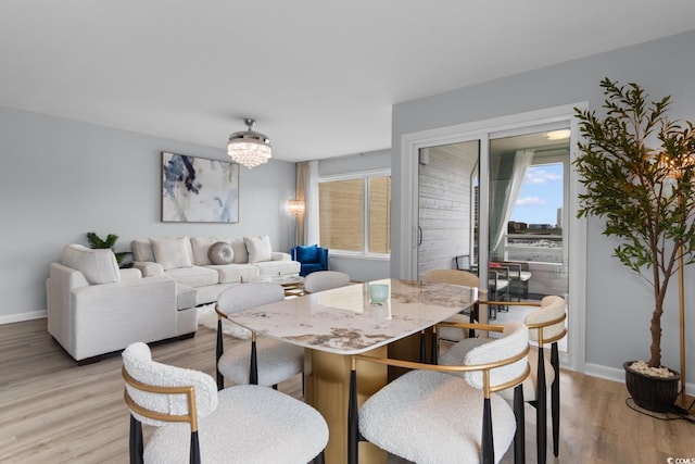 dining space with light wood finished floors, baseboards, and a chandelier