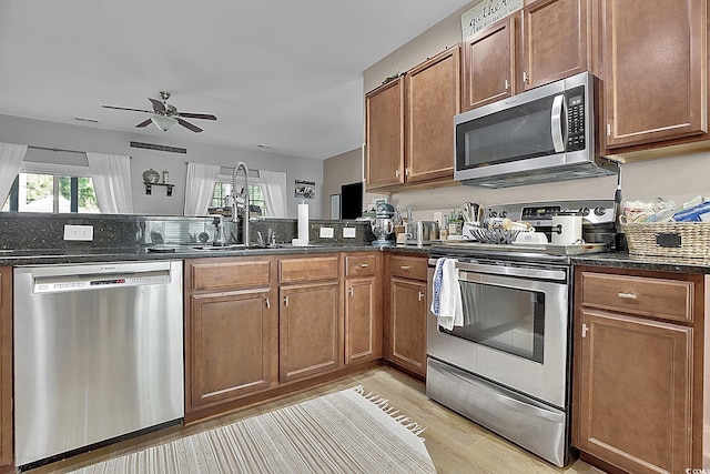 9232 Goodwill Ct, Myrtle Beach, SC 29579 - kitchen with appliances with stainless steel finishes, a sink, ceiling fan, light wood-style flooring, and brown cabinetry