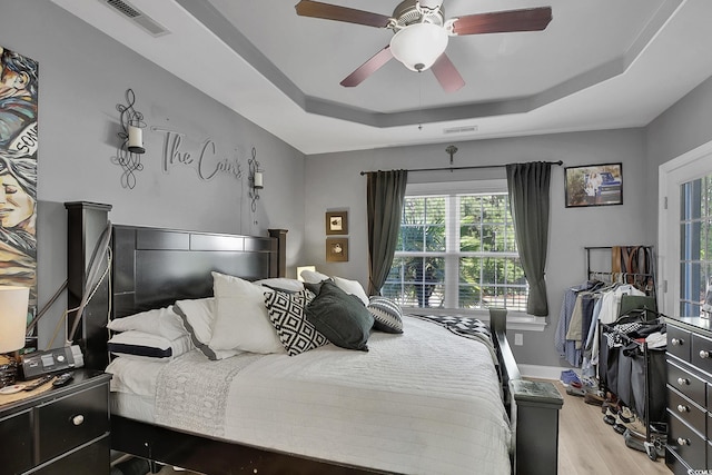 9232 Goodwill Ct, Myrtle Beach, SC 29579 - bedroom with a raised ceiling, light wood-style flooring, a ceiling fan, and baseboards