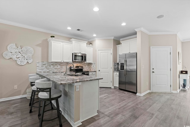 448 Papyrus Cir Unit 448, Little River, SC 29566 - kitchen featuring appliances with stainless steel finishes, a peninsula, white cabinets, a kitchen bar, and light stone countertops