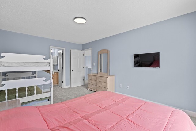 bedroom featuring light colored carpet, baseboards, and ensuite bath