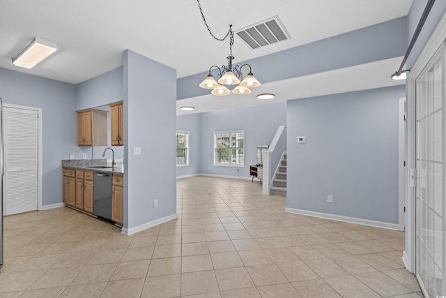 kitchen featuring dishwasher, a sink, a chandelier, open floor plan, and pendant lighting