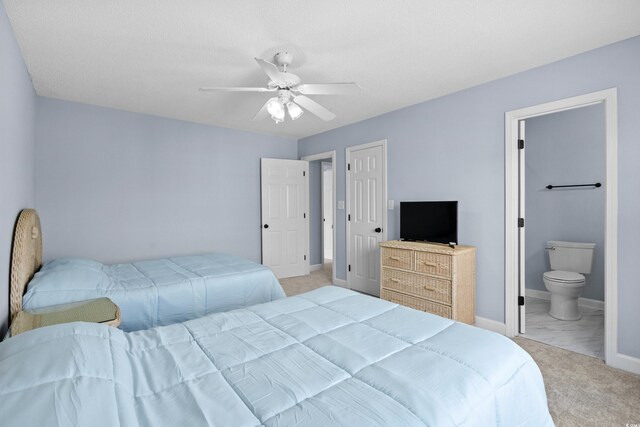 bedroom featuring baseboards, light colored carpet, ensuite bathroom, and a ceiling fan