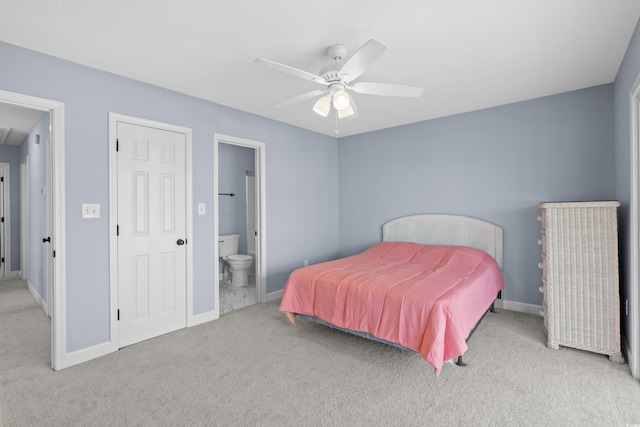 carpeted bedroom featuring baseboards, ensuite bath, and a ceiling fan