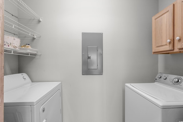 laundry area with electric panel, separate washer and dryer, and cabinet space
