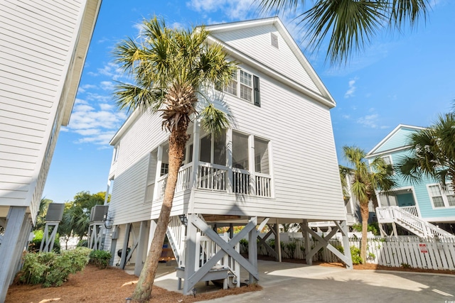 rear view of property with a carport, fence, a sunroom, driveway, and stairs