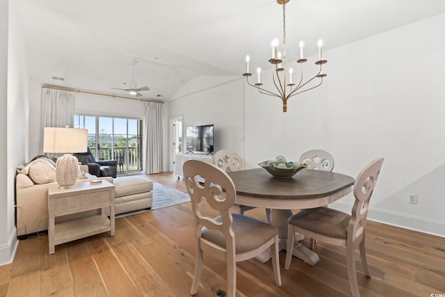 dining room featuring vaulted ceiling, light wood-type flooring, baseboards, a chandelier, and a ceiling fan