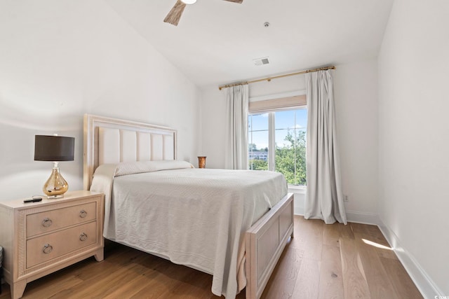 bedroom featuring light wood-style flooring, vaulted ceiling, a ceiling fan, and baseboards
