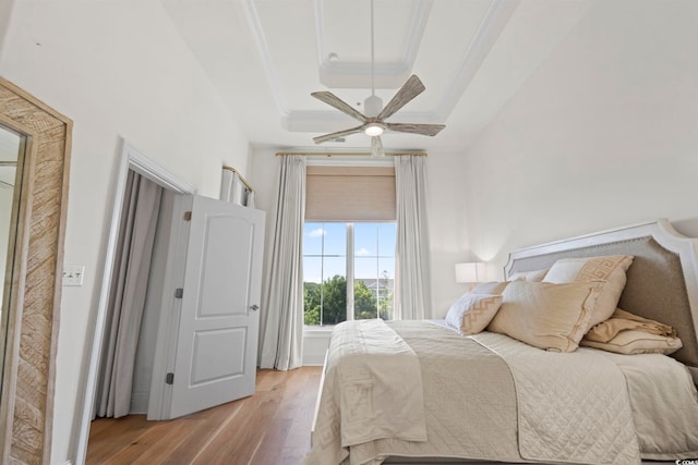 bedroom with wood finished floors, a tray ceiling, and a ceiling fan