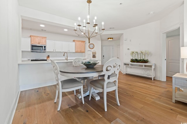 dining space featuring a chandelier, light wood-type flooring, recessed lighting, and baseboards