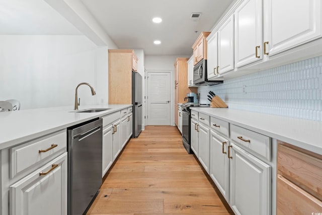 kitchen featuring a sink, appliances with stainless steel finishes, light countertops, recessed lighting, and light wood-type flooring