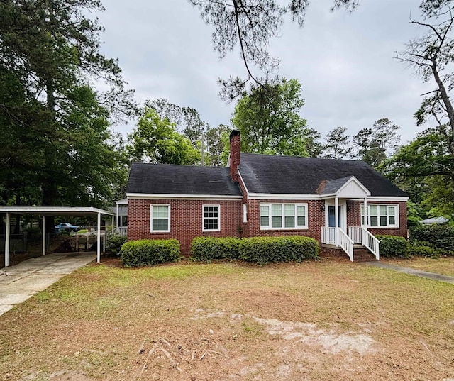 307 Pressley Ave, Kingstree, SC 29556 - view of front facade with brick siding, a front lawn, a carport, a chimney, and driveway