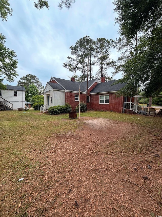 307 Pressley Ave, Kingstree, SC 29556 - rear view of house featuring a chimney, brick siding, and a lawn