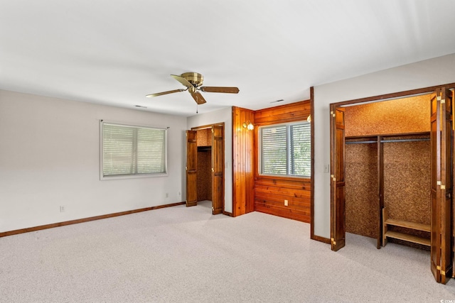 1314 Holly Dr, North Myrtle Beach, SC 29582 - unfurnished bedroom with light carpet, two closets, wood walls, a ceiling fan, and baseboards