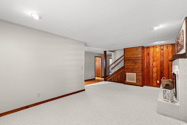 1314 Holly Dr, North Myrtle Beach, SC 29582 - unfurnished living room with carpet floors, stairs, baseboards, a fireplace, and wood walls