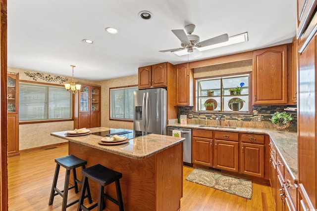 1314 Holly Dr, North Myrtle Beach, SC 29582 - kitchen featuring stainless steel appliances, brown cabinetry, a breakfast bar area, light wood finished floors, and recessed lighting