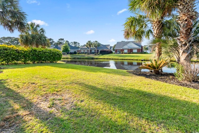 view of grassy yard with a water view and a residential view