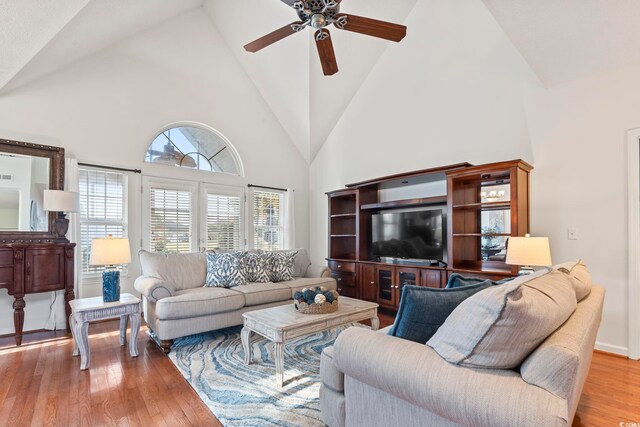 living area with high vaulted ceiling, a ceiling fan, and wood finished floors