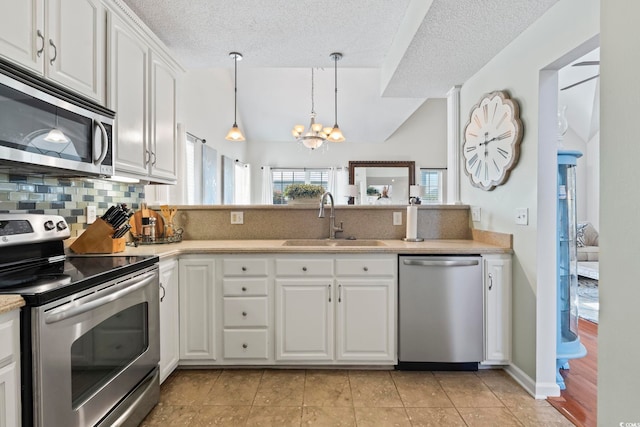 kitchen with stainless steel appliances, a sink, tasteful backsplash, light countertops, and a chandelier