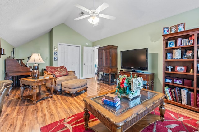 living room with a ceiling fan, wood finished floors, and lofted ceiling