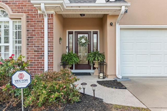 doorway to property with stucco siding, an attached garage, and brick siding