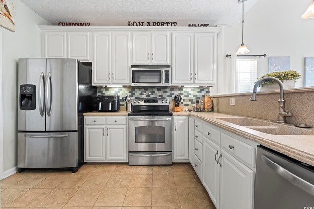 kitchen with stainless steel appliances, a sink, tasteful backsplash, light countertops, and a textured ceiling