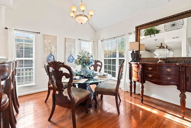 dining room featuring a chandelier, light wood finished floors, high vaulted ceiling, and baseboards