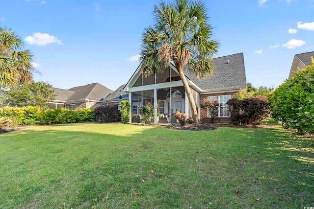 back of house featuring a sunroom, a yard, and brick siding