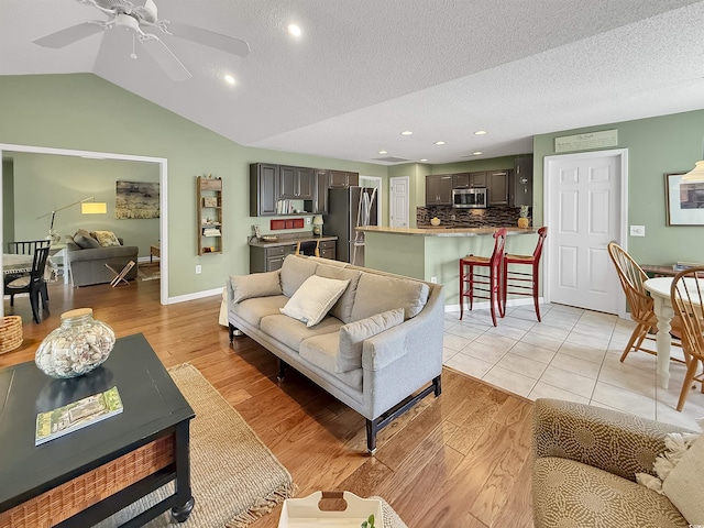 living area featuring light wood-style flooring, recessed lighting, a ceiling fan, lofted ceiling, and a textured ceiling