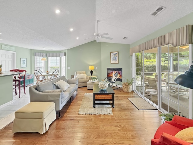 living area featuring a textured ceiling, a ceiling fan, vaulted ceiling, recessed lighting, and light wood-style floors