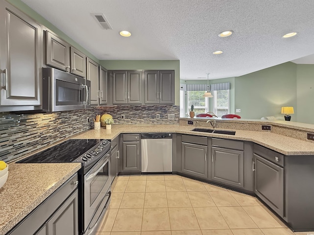 kitchen featuring stainless steel appliances, a sink, gray cabinetry, backsplash, and recessed lighting
