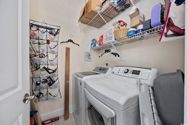 laundry area featuring washing machine and clothes dryer, baseboards, and light tile patterned flooring
