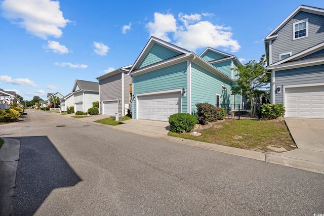 view of front of property featuring a residential view, fence, and a garage