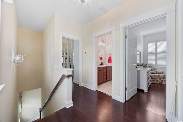 hallway with an upstairs landing, dark wood-style floors, and baseboards
