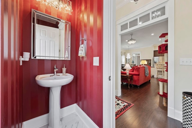 bathroom with a chandelier, baseboards, crown molding, and wood finished floors