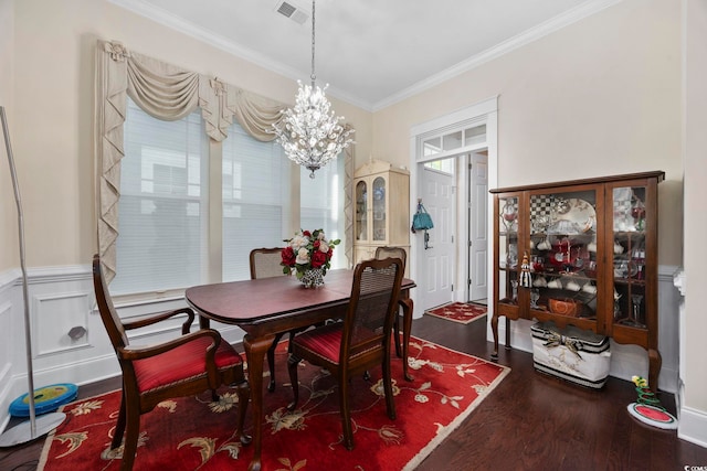 dining space with wood finished floors, ornamental molding, a chandelier, and a wainscoted wall