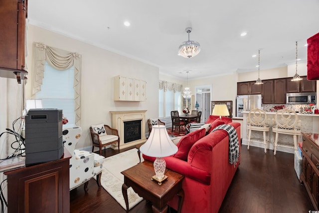 living area featuring a chandelier, dark wood finished floors, crown molding, recessed lighting, and a fireplace