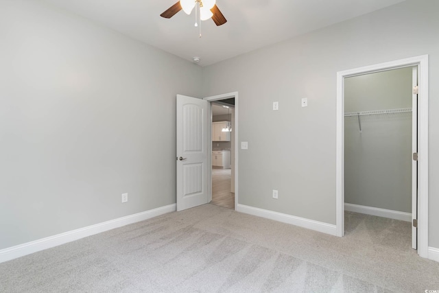 unfurnished bedroom featuring carpet floors, a spacious closet, baseboards, a closet, and a ceiling fan