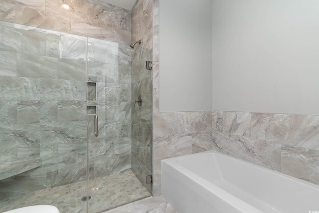 full bathroom featuring a garden tub, a stall shower, and toilet