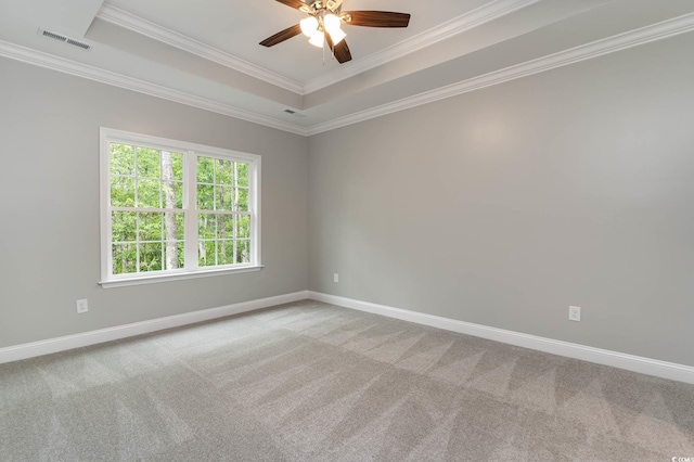 spare room with crown molding, a tray ceiling, a ceiling fan, baseboards, and carpet floors