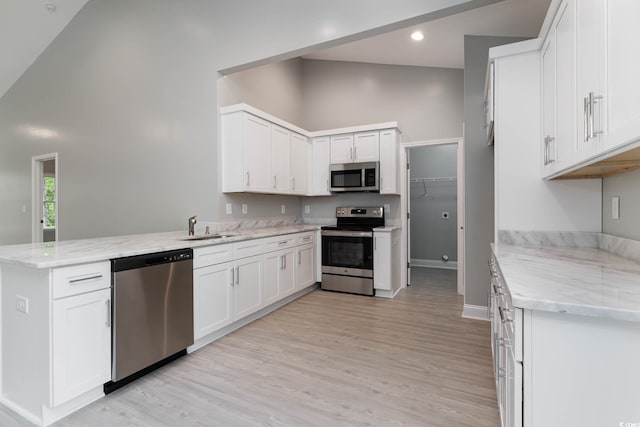 kitchen with stainless steel appliances, a peninsula, a sink, high vaulted ceiling, and light stone countertops