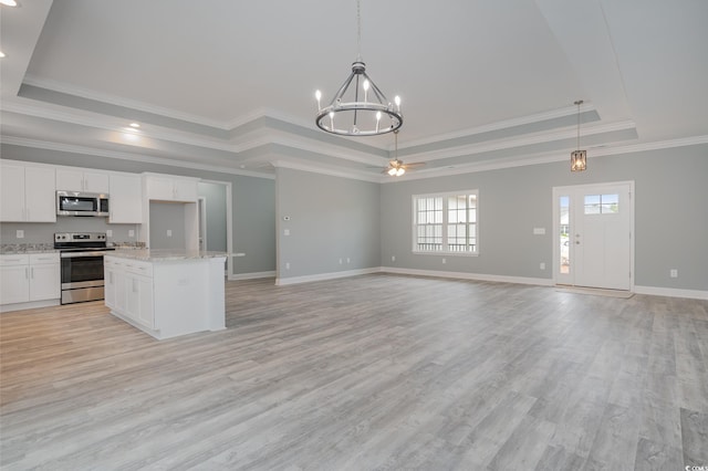 kitchen with stainless steel appliances, a raised ceiling, a chandelier, open floor plan, and light wood-style flooring