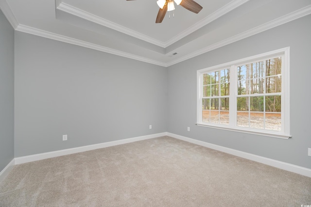 spare room featuring a tray ceiling, a ceiling fan, carpet, crown molding, and baseboards