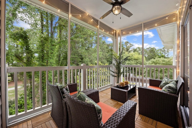 sunroom featuring outdoor lounge area, ceiling fan, and view of scattered trees