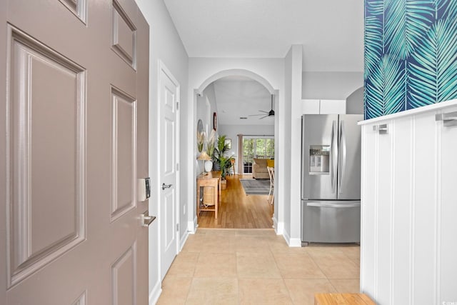entrance foyer with a ceiling fan, baseboards, arched walkways, and light tile patterned floors