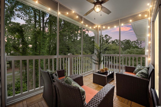 sunroom with an outdoor hangout area, ceiling fan, and view of wooded area