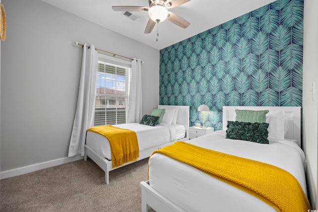 bedroom featuring carpet floors, an accent wall, baseboards, and a ceiling fan
