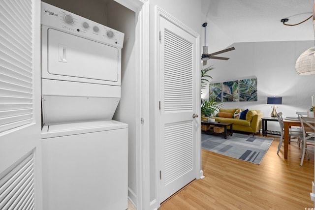 washroom featuring stacked washer / drying machine, a ceiling fan, and light wood-style flooring