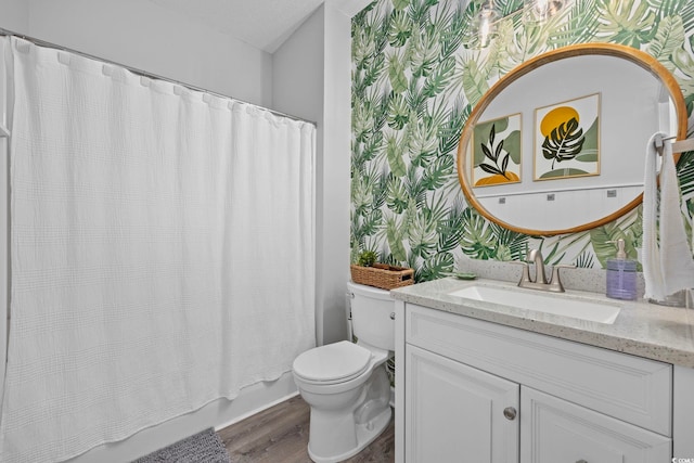 bathroom with wallpapered walls, wood finished floors, toilet, vanity, and shower / bath combo