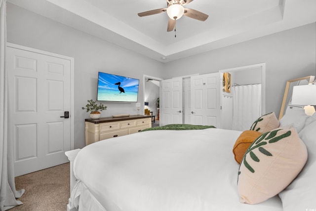 bedroom with carpet flooring, a raised ceiling, and a ceiling fan